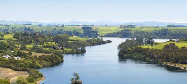 Ein großer See umgeben von Feldern und Bäumen
