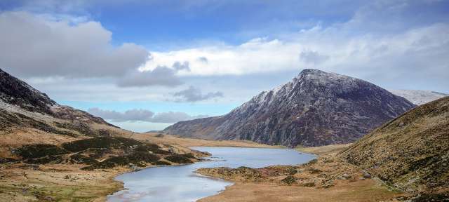 Snowdonia: menschenleere Fjorde und Küsten Ein See inmitten einer Bergkette mit einem schneebedeckten Berg im Hintergrund