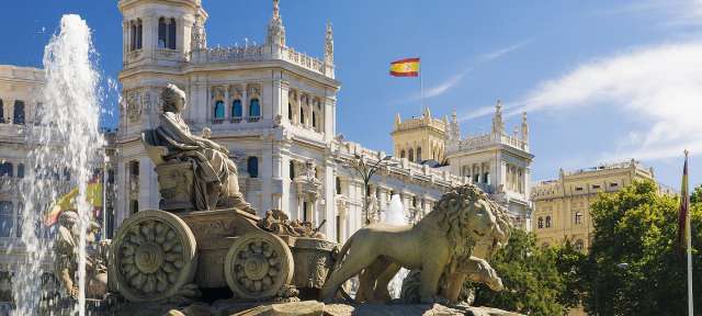 Kultureller Mittelpunkt Spaniens: Madrid Ein Brunnen mit Löwen und einer spanischen Flagge im Hintergrund