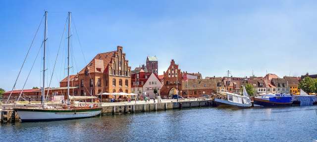 Wismar Ein weißes Boot mit einem grünen Segel sitzt in einem Hafen