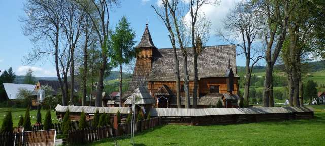 Reisefoto von – ©Sandra Schaaf, Umfulana Eine hölzerne Kirche mit einem Turm und einem Zaun umgeben von Bäumen
