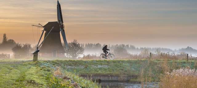 Eine Person fährt mit einem Fahrrad in der Nähe einer Windmühle
