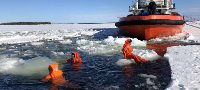 Ein Abenteuer: Schwimmen im Eis Menschen in orangefarbenen Anzügen schwimmen in einem zugefrorenen See