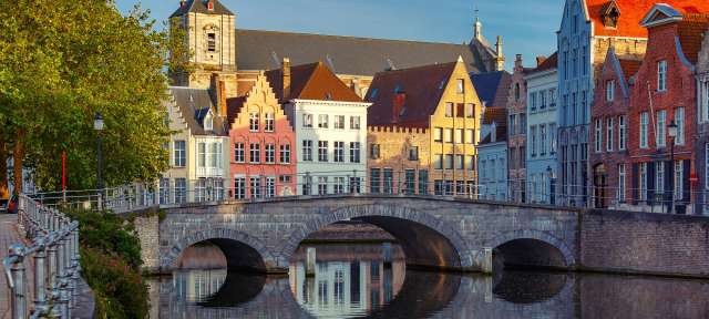 Brügge Eine Brücke über einen Fluss mit bunten Gebäuden im Hintergrund