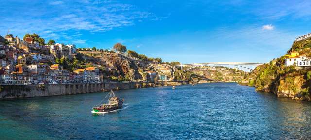 Porto Ein Boot fährt auf einem Fluss mit einer Brücke im Hintergrund