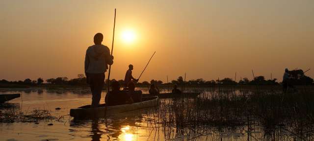 Eine Gruppe von Menschen paddelt auf einem See bei Sonnenuntergang