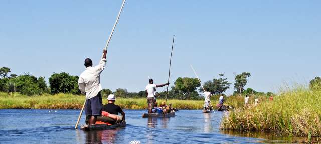Im Einboot durch die Wildnis: Okavango Delta Eine Gruppe von Menschen paddelt auf einem Fluss