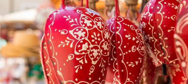 Verzierte Kuhglocken Rote Glocken mit weißen Blumenmustern hängen an einem Seil