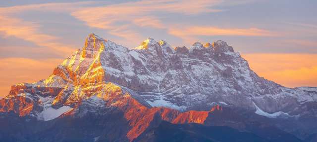Panoramasicht auf den Dents du Midi in den Schweizer Alpen Ein schneebedeckter Berg mit orangefarbenem Himmel im Hintergrund