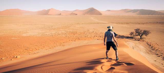 Ein Mann steht auf einer Sanddüne in der Wüste