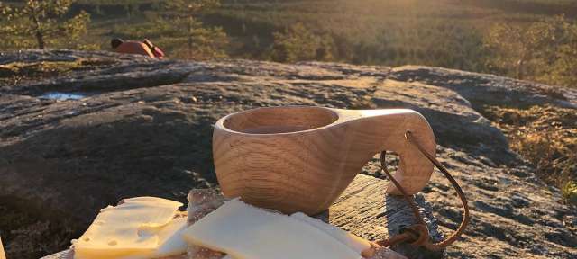 Eine Tasse Kaffee steht auf einem Felsen neben einem Stück Brot und Käse