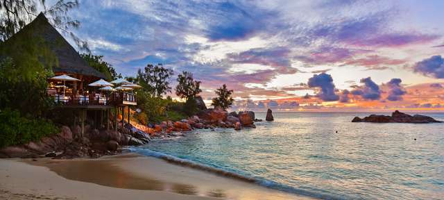 Ein Sonnenuntergang am Strand mit einem Restaurant im Hintergrund