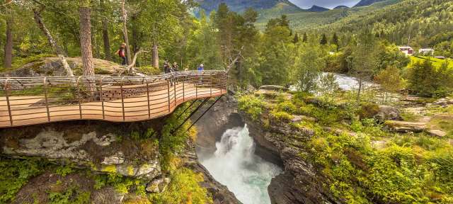Menschen stehen auf einer Brücke über einen Wasserfall