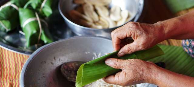 Bananenblätter: Bestandteil Asiens frischer Küche Eine Person wickelt ein Bananenblatt über einen Haufen Reis