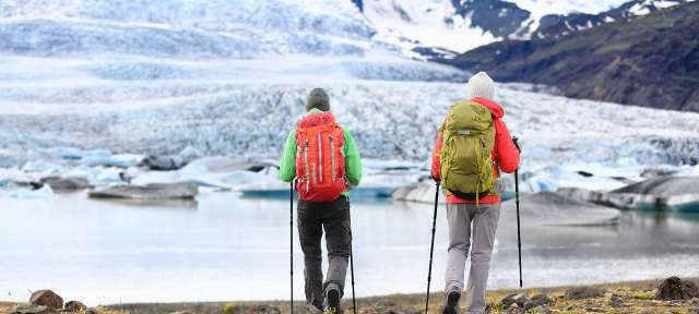 Aktivreisen: Wandern auf Island Zwei Menschen mit Rucksäcken gehen an einem See entlang