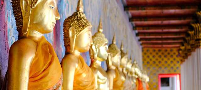 Wat Arun: Buddhistischer Tempel in Bangkok Eine Reihe von goldenen buddhistischen Statuen in einem Tempel