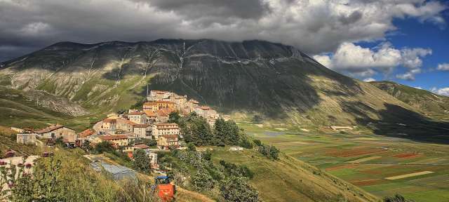 Landschaft in den Marken: Casteluccio Ein Dorf auf einem Hügel mit einem Berg im Hintergrund