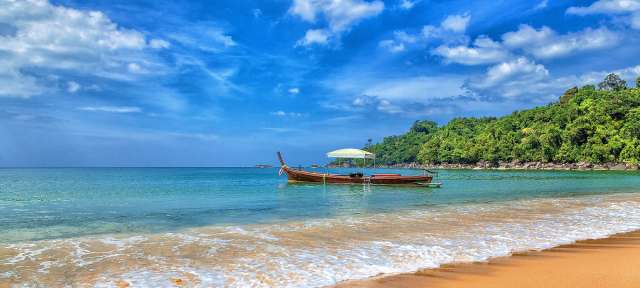Bekannt für seine fantastischen Sandstrände: Khao Lak Ein kleines Boot mit einem Regenschirm sitzt am Strand
