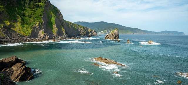 Kleine Inseln vor dem spanischen Baskenland Eine felsige Küste mit einem großen Felsen in der Mitte des Ozeans