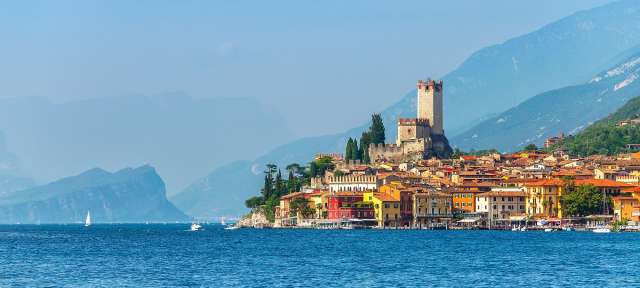 Gardasee Eine Stadt am Ufer eines Sees mit Bergen im Hintergrund