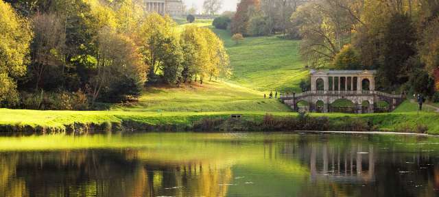 Ein Teich in einem Park mit einem Gebäude im Hintergrund