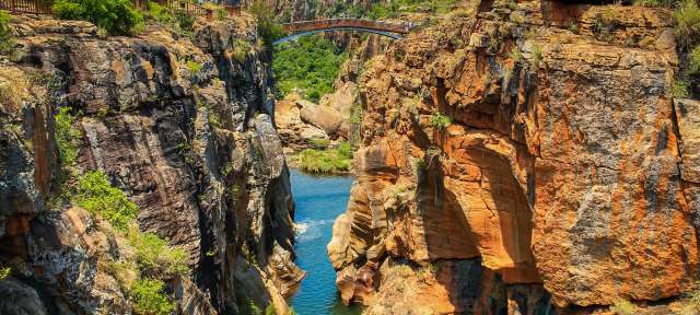 Brücke über den Canyon bei den Bourke's Luck Potholes im Flu Eine Brücke über einen Fluss zwischen zwei Felsen