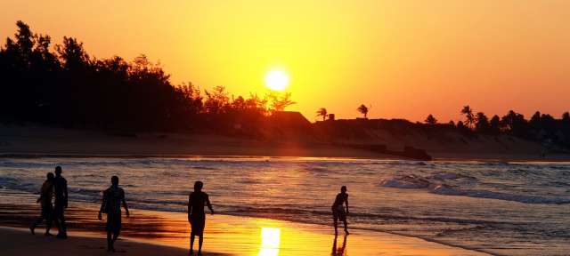 Eine Gruppe von Menschen geht bei Sonnenuntergang am Strand spazieren