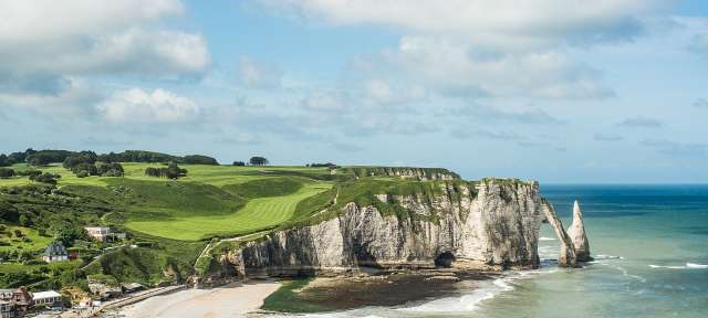 Die Küsten der Normandie Ein Strand mit einem großen Felsen im Hintergrund