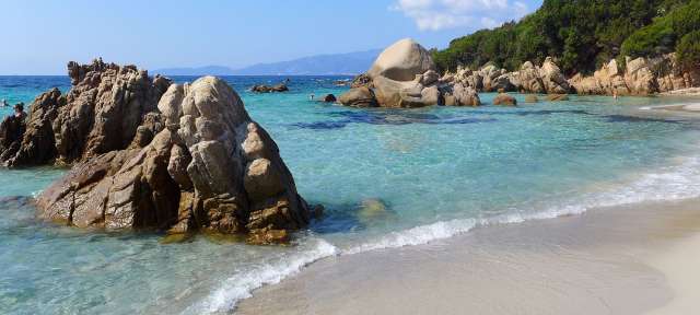 Ein Strand mit einem großen Felsen in der Mitte