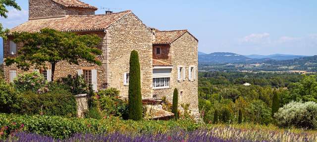 Lavendelfelder in der Provence Ein großes Steingebäude steht auf einem Hügel neben einem Lavendelfeld