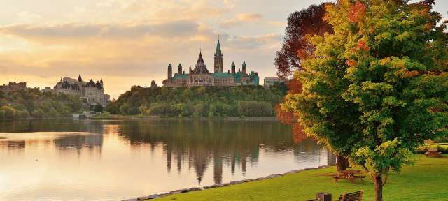 Ottawa City Skyline bei Sonnenaufgang Ein großes Gebäude sitzt auf einem Hügel über einem See