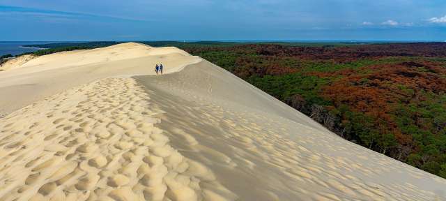 Zwei Menschen stehen auf einer Sanddüne mit Blick auf den Ozean