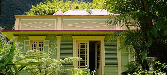 Typische Architektur: La Réunion Ein grünes und gelbes Haus mit einem rosa Dach