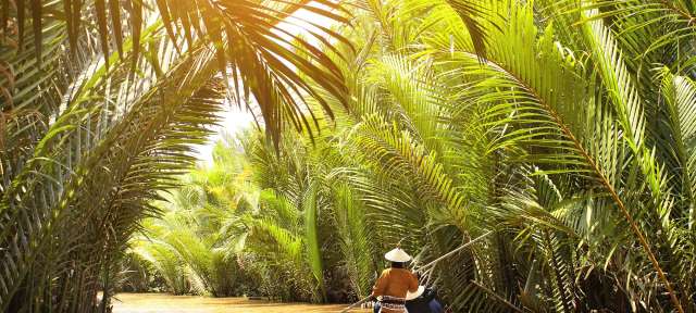 Vietnam: Unterwegs auf dem Mekong-Fluss Ein Mann paddelt in einem kleinen Boot auf einem Fluss
