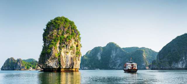 Vietnam: Halong Bay Ein Boot schwimmt in einem See mit einem großen Felsen im Hintergrund