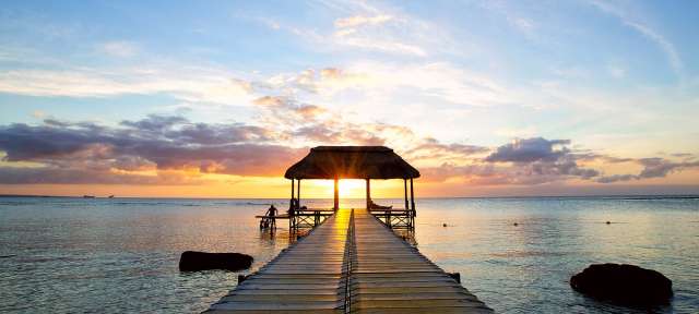 Steeg in der Abendsonne: Mauritius Ein Holzsteg mit einem Strohdach führt ins Meer