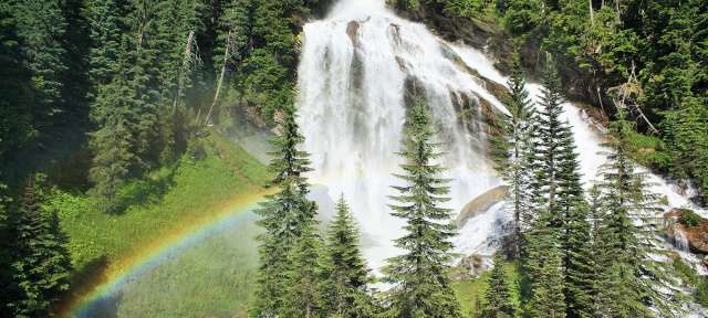Ein Wasserfall im Wald mit einem Regenbogen davor