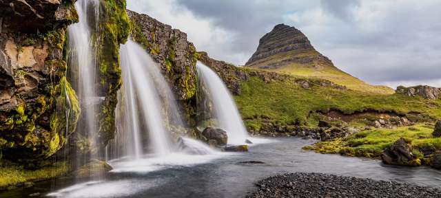Kirkjufellsfoss: Wasserfall im Westen Islands Ein Wasserfall mit einem Berg im Hintergrund