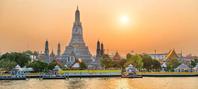 Bangkok. Blick auf den Tempel Wat Arun Ein kleines Boot fährt auf einem Fluss in der Nähe eines großen Gebäudes