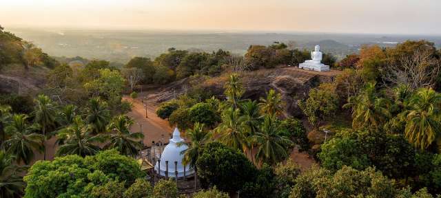 Sri Lanka: Buddhistischer Tempel in Mihintale Eine buddhistische Statue sitzt auf einem Hügel inmitten eines Dschungels