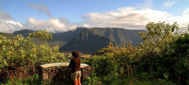 Den Ausblick genießen: Wandern auf La Réunion Eine Frau steht vor einem Schild und schaut auf die Berge