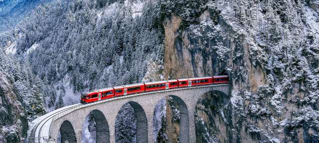65 Meter hoch, 136 Meter lang: Landwasserviadukt Ein roter Zug fährt über eine Brücke in den Bergen