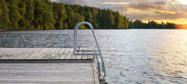 Frischer Start in den Tag: See Ein Holzdock mit einer Treppe, die ins Wasser führt
