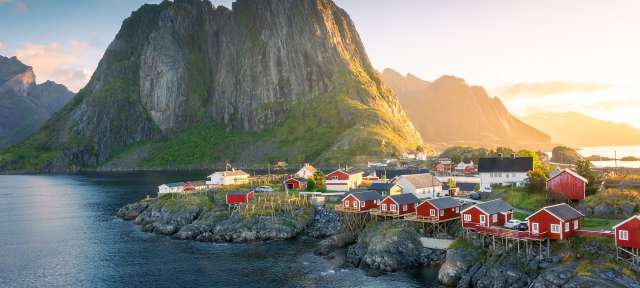 Die kleine Stadt Reine: Lofoten Ein Dorf mit roten Häusern und einem großen Berg im Hintergrund