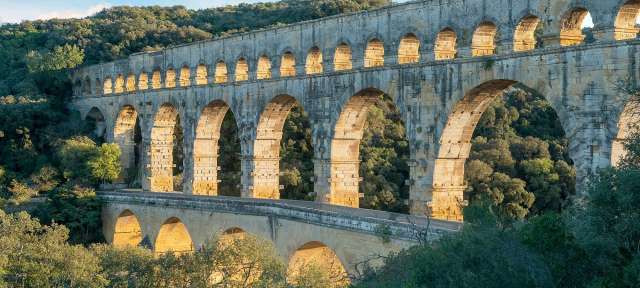 Römisches Aquädukt im Süden Frankreichs: Pont du Gard Eine Brücke mit vielen Bogen führt durch einen Wald