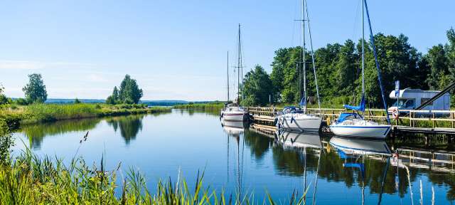 Am Göta-Kanal Eine Reihe von Booten, die an einem Dock an einem Fluss festgemacht sind