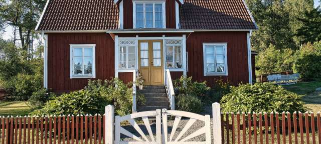 Ein rotes Haus mit weißen Fenstern und einem weißen Zaun