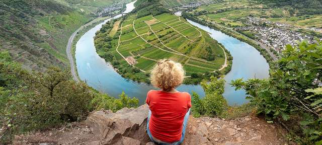 Blick auf die Moselschleife: Soloreise Deutschland Eine Frau sitzt auf einem Felsen mit Blick auf einen Fluss