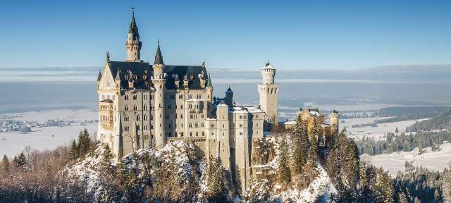 Ein großes Schloss sitzt auf einem schneebedeckten Hügel
