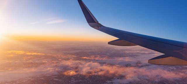 Ein Flugzeug fliegt bei Sonnenuntergang über den Wolken